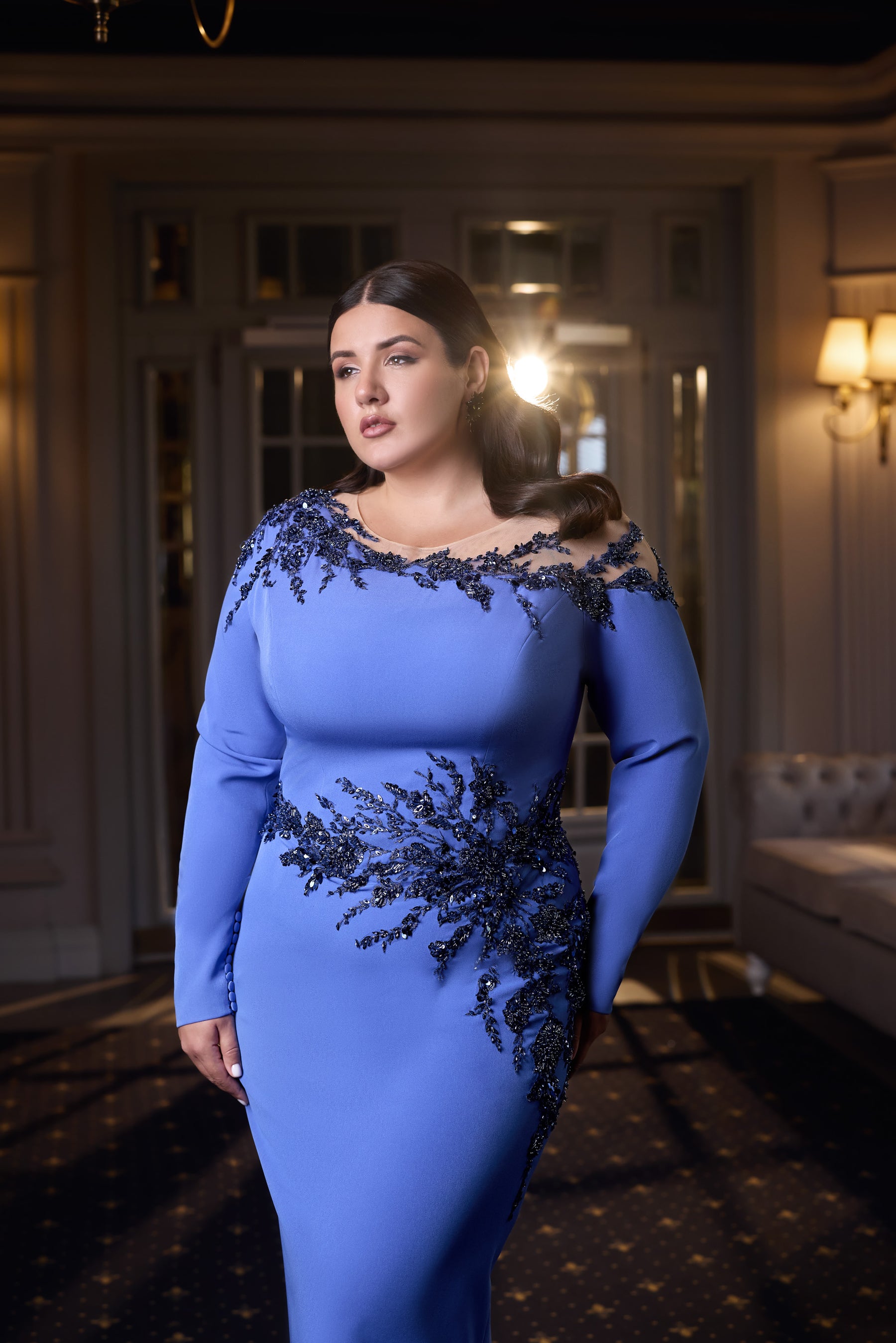 Fitted blue evening dress with long sleeves, an off-shoulder neckline, and dark floral beadwork