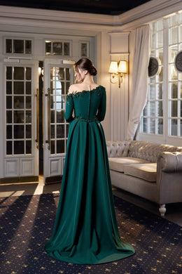 Back of an emerald green evening dress with long sleeves, a cinched waist, full skirt, and train