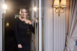 Black evening dress with an asymmetrical neckline, long sleeves, and sparkling floral embellishment