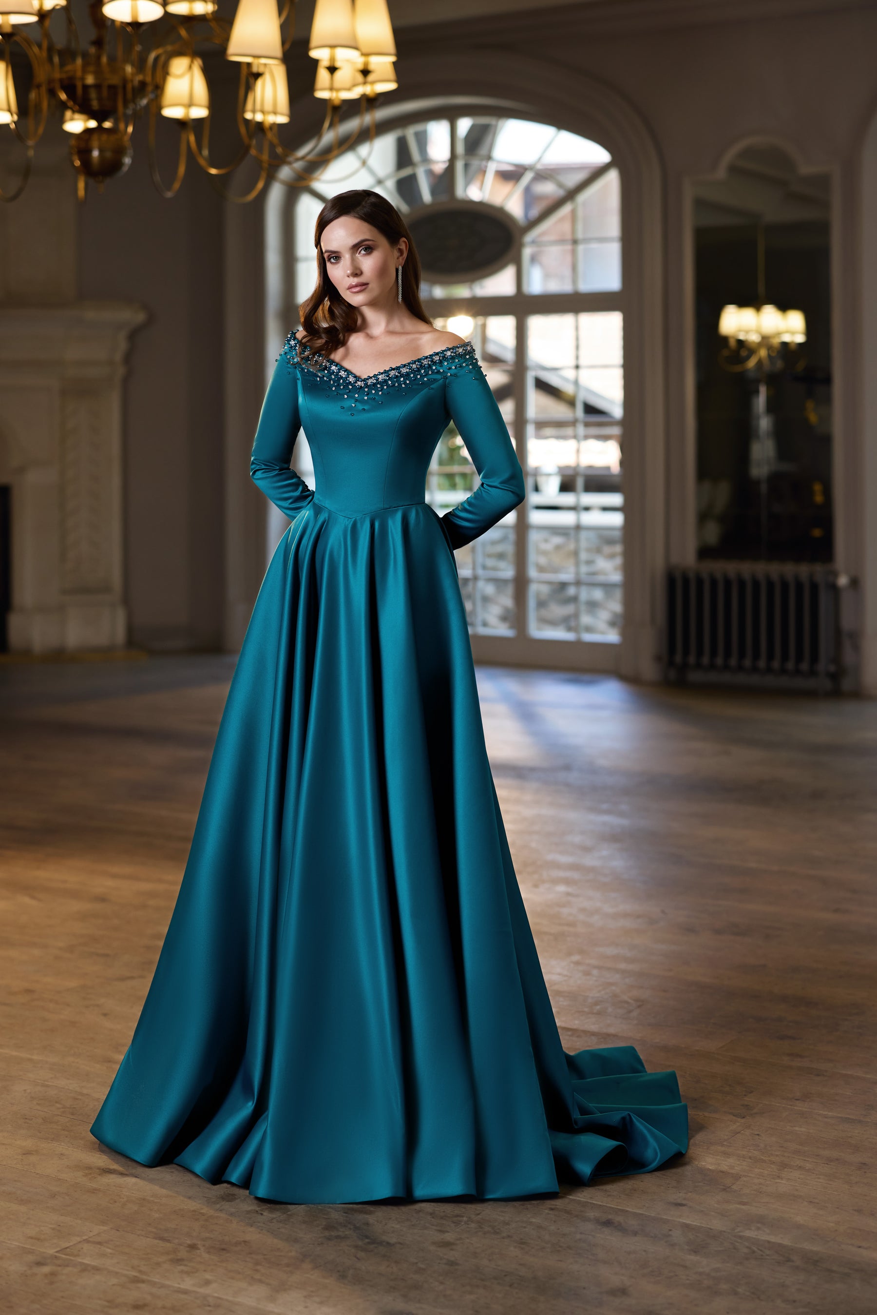 Teal floor-length evening dress with an embellished off-the-shoulder neckline, long sleeves, and a flowing train