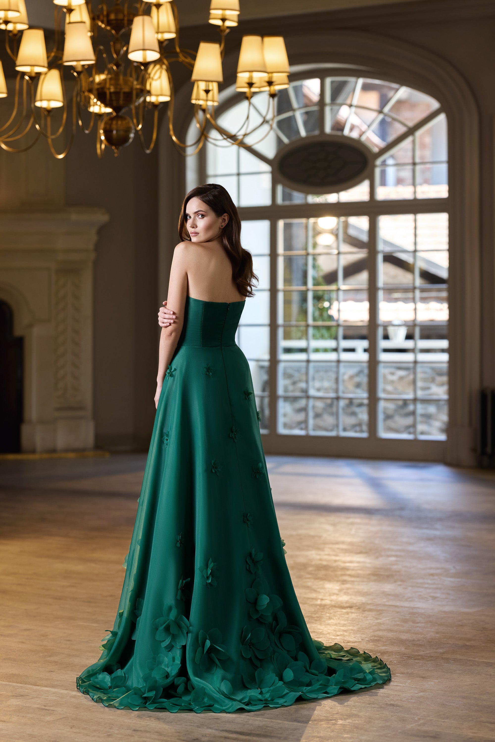 Emerald green strapless evening dress with a floral-appliquéd skirt, sweeping train, and decorated hem