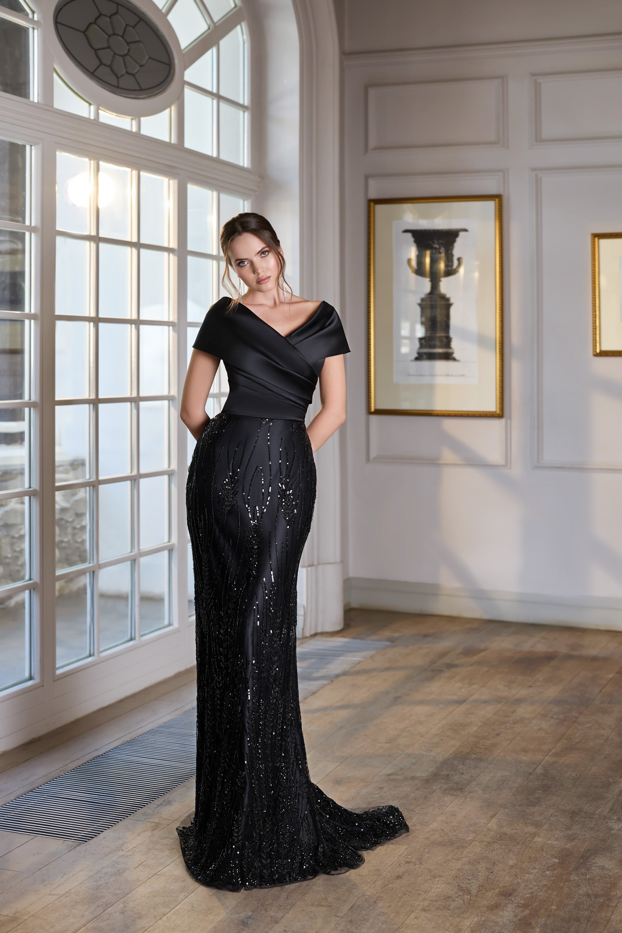 Black sequined evening dress with a draped crossover neckline, short sleeves, fitted silhouette, and sweeping train
