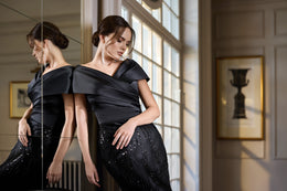 Close-up of a black evening dress featuring a crossover neckline, cap sleeves, and sparkling sequin embellishment