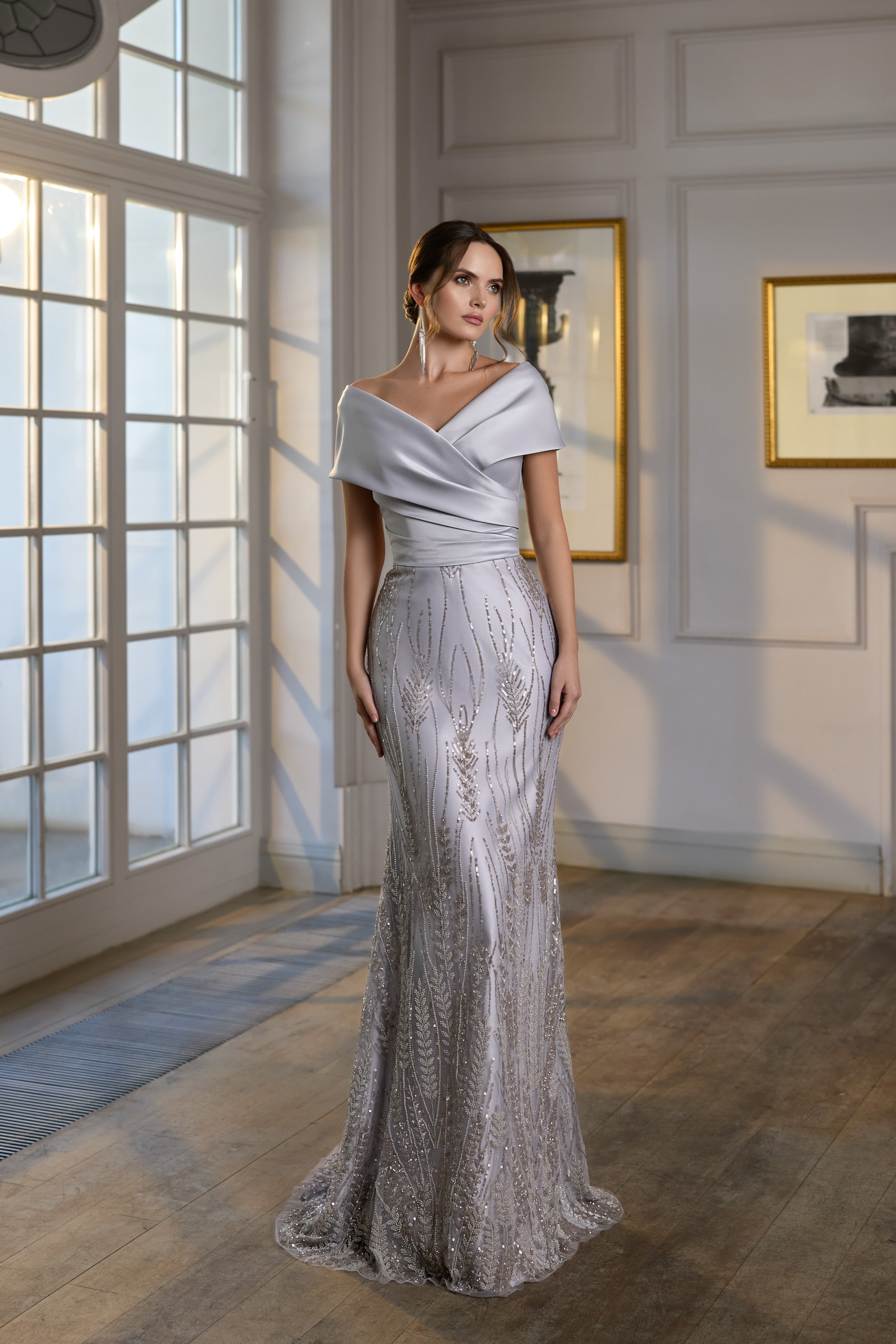 Silver evening dress with an off-the-shoulder neckline, fitted silhouette, shimmering embellishment, and trailing hem