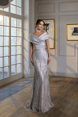 Silver evening dress with an off-the-shoulder neckline, fitted silhouette, shimmering embellishment, and trailing hem