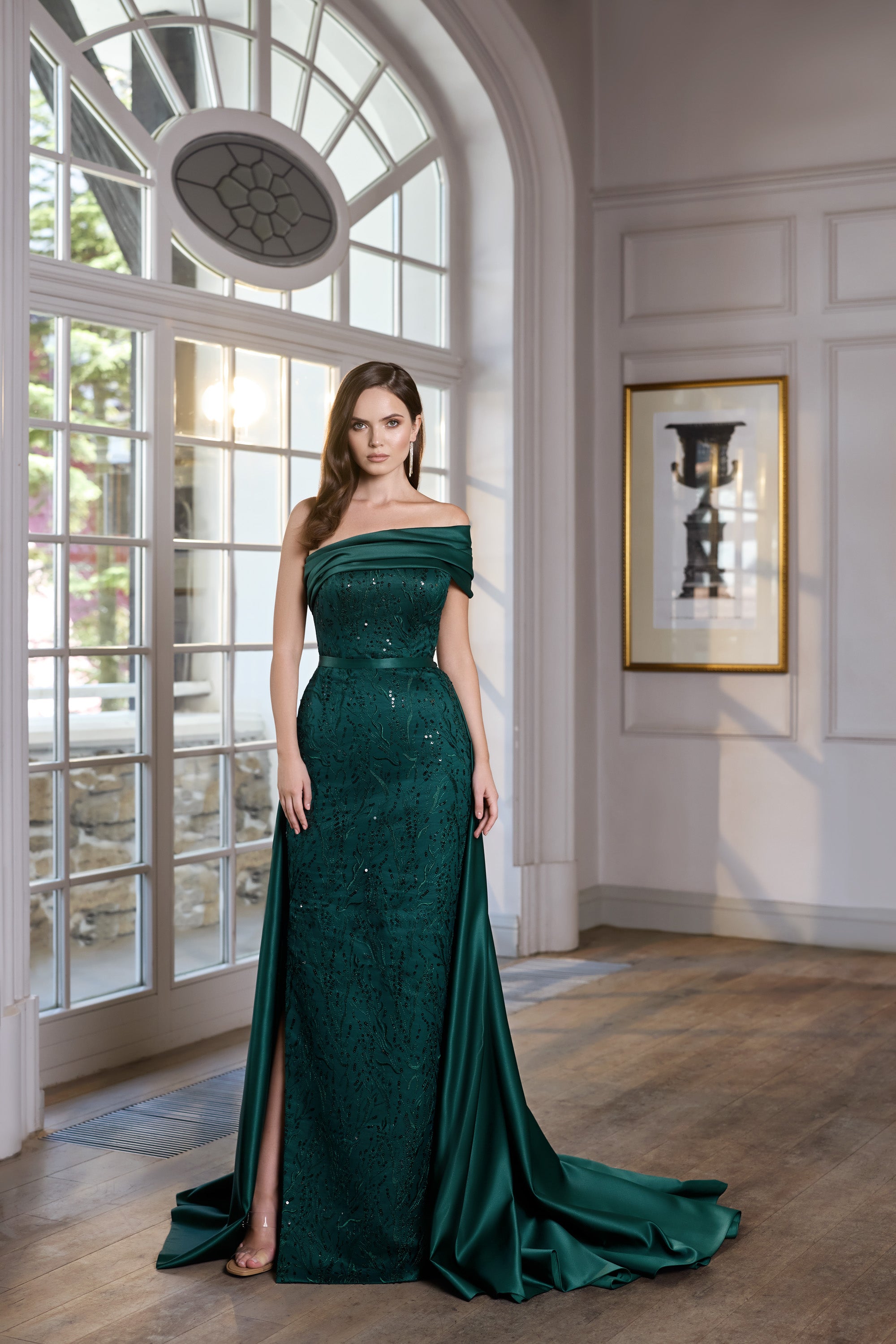 Teal evening dress with an off-shoulder neckline, fitted silhouette, shimmering texture, and sweeping train