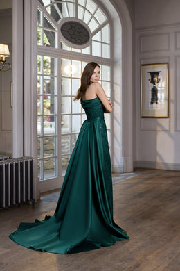 Teal evening dress shown from the back with a fitted bodice and long, flowing train
