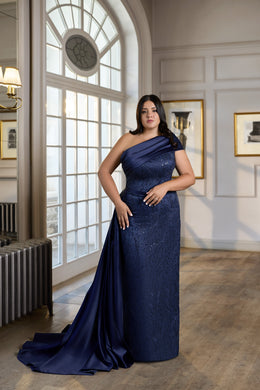 Navy evening dress with an asymmetrical draped neckline, fitted column silhouette, and trailing side panel