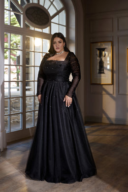 Black evening dress with a square neckline, sheer long sleeves, sparkling details, and a full floor-length skirt