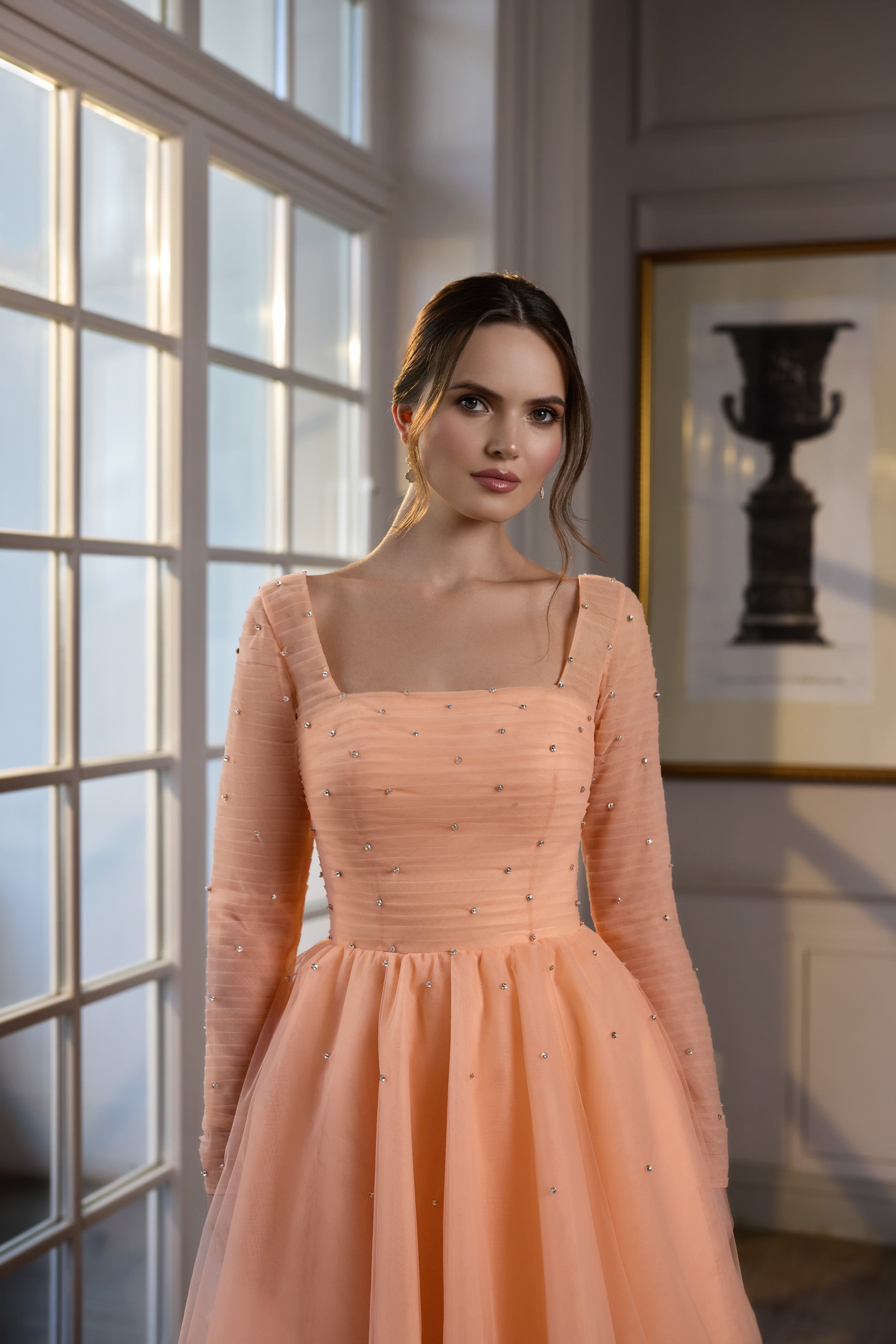 Peach evening dress with a square neckline, sheer long sleeves, scattered bead accents, and a gathered full skirt