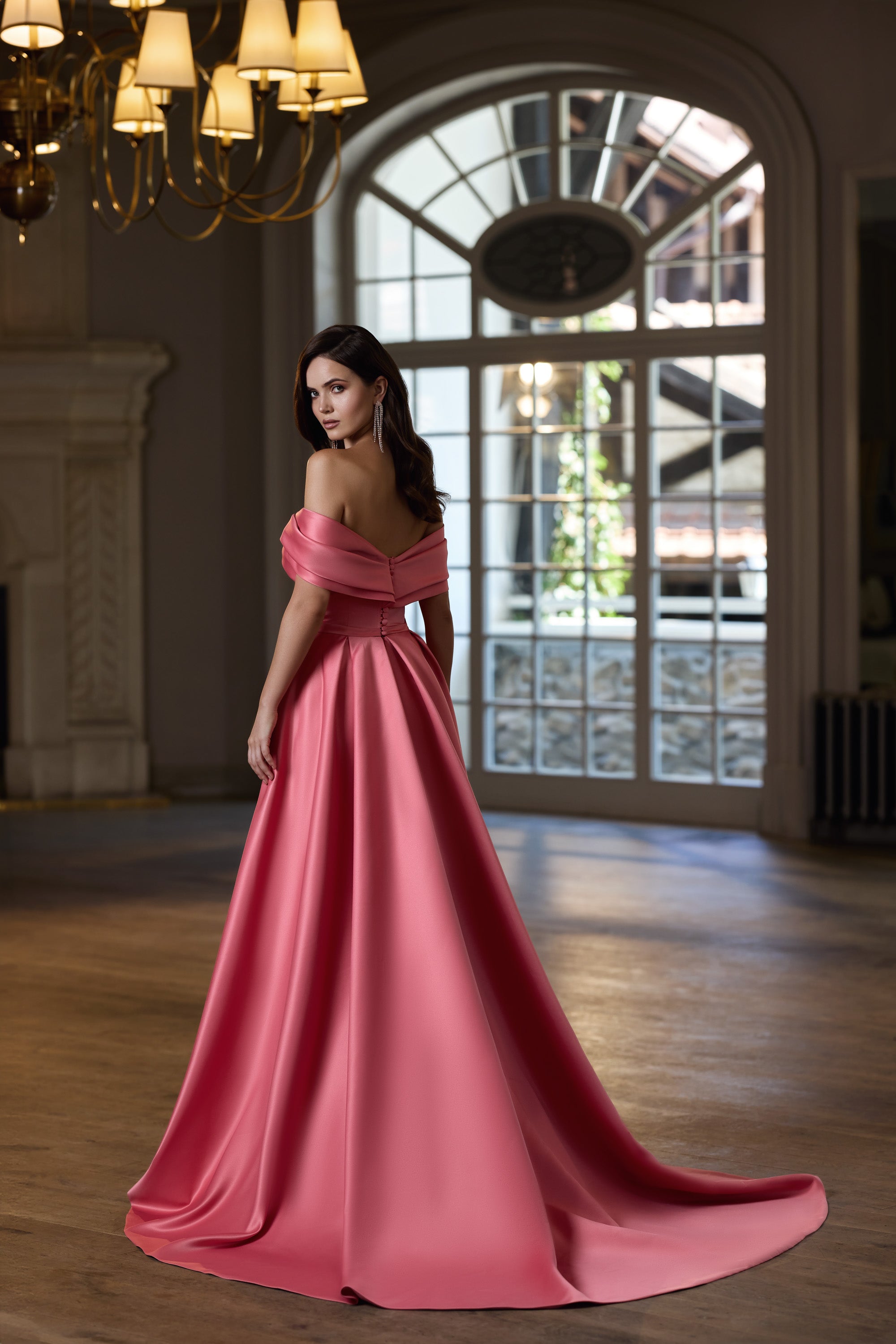 Rose pink evening dress showing an off-the-shoulder back, fitted waist, and sweeping floor-length train