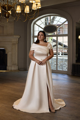 Ivory evening dress with a draped off-the-shoulder neckline, fitted waist, high side slit, and train