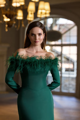 Emerald green evening dress with an off-the-shoulder neckline, long sleeves, and feather trim