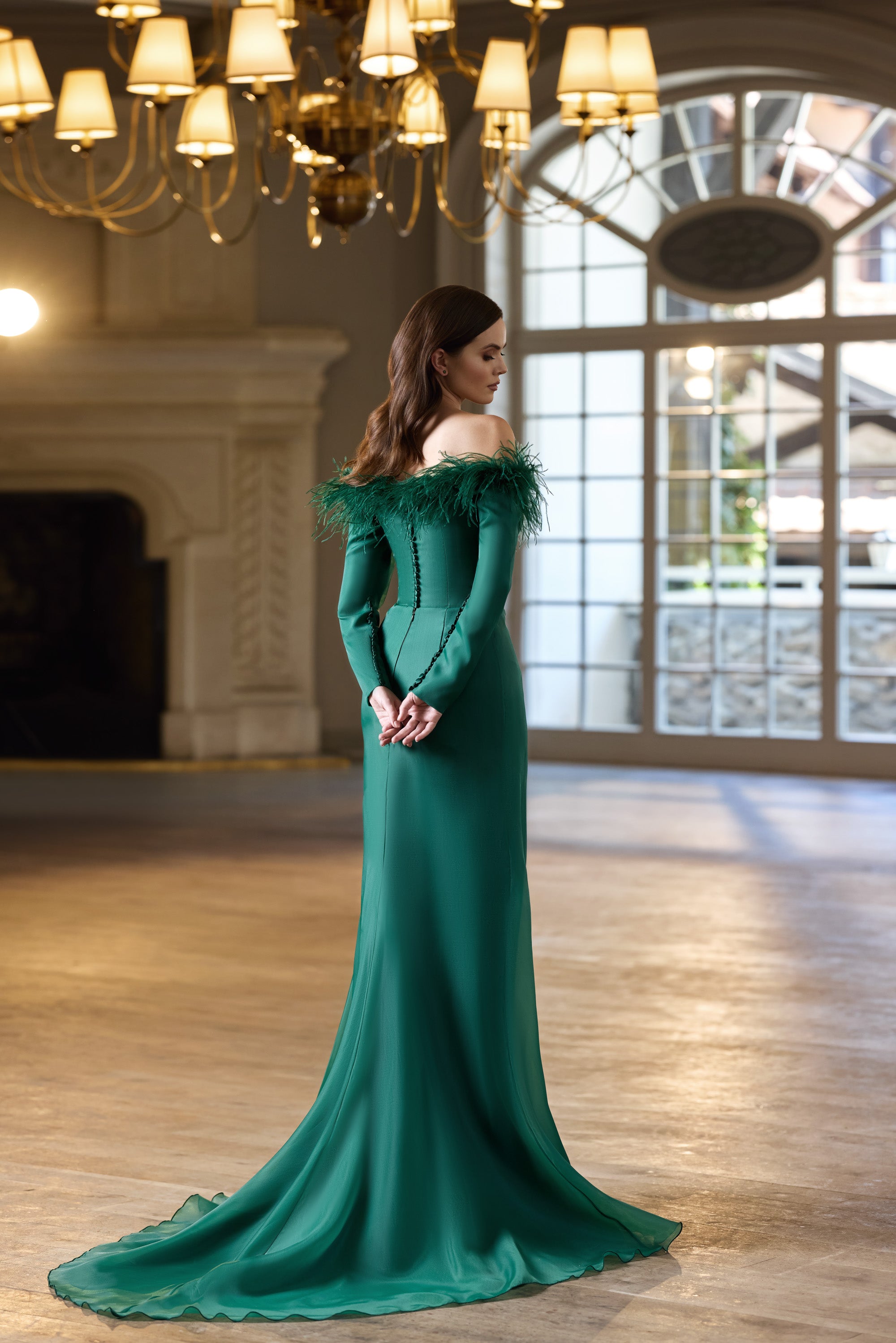 Emerald green mermaid evening dress with a feathered neckline and sweeping floor-length train