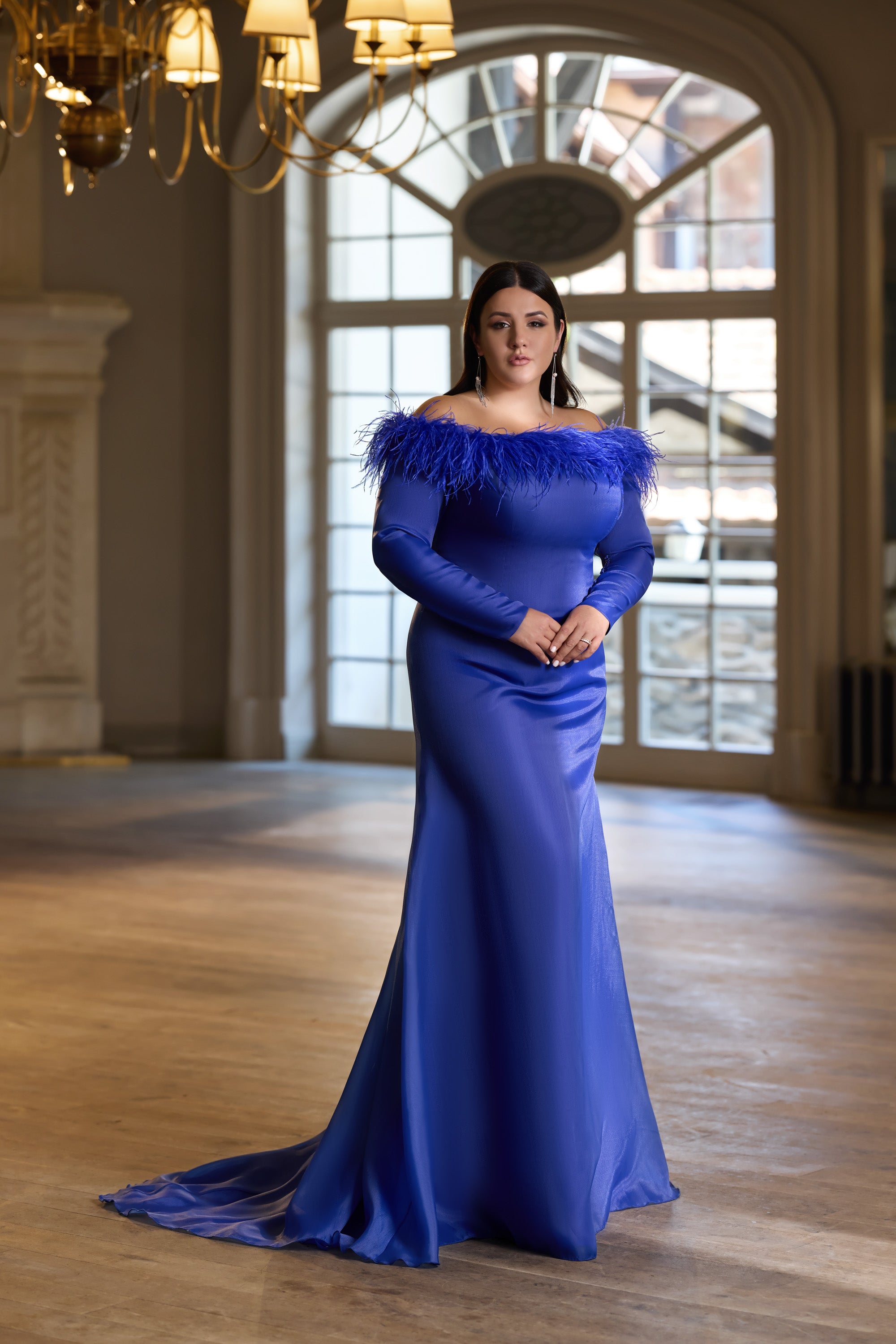Sapphire blue evening dress with a feather-trimmed off-the-shoulder neckline and long flowing train