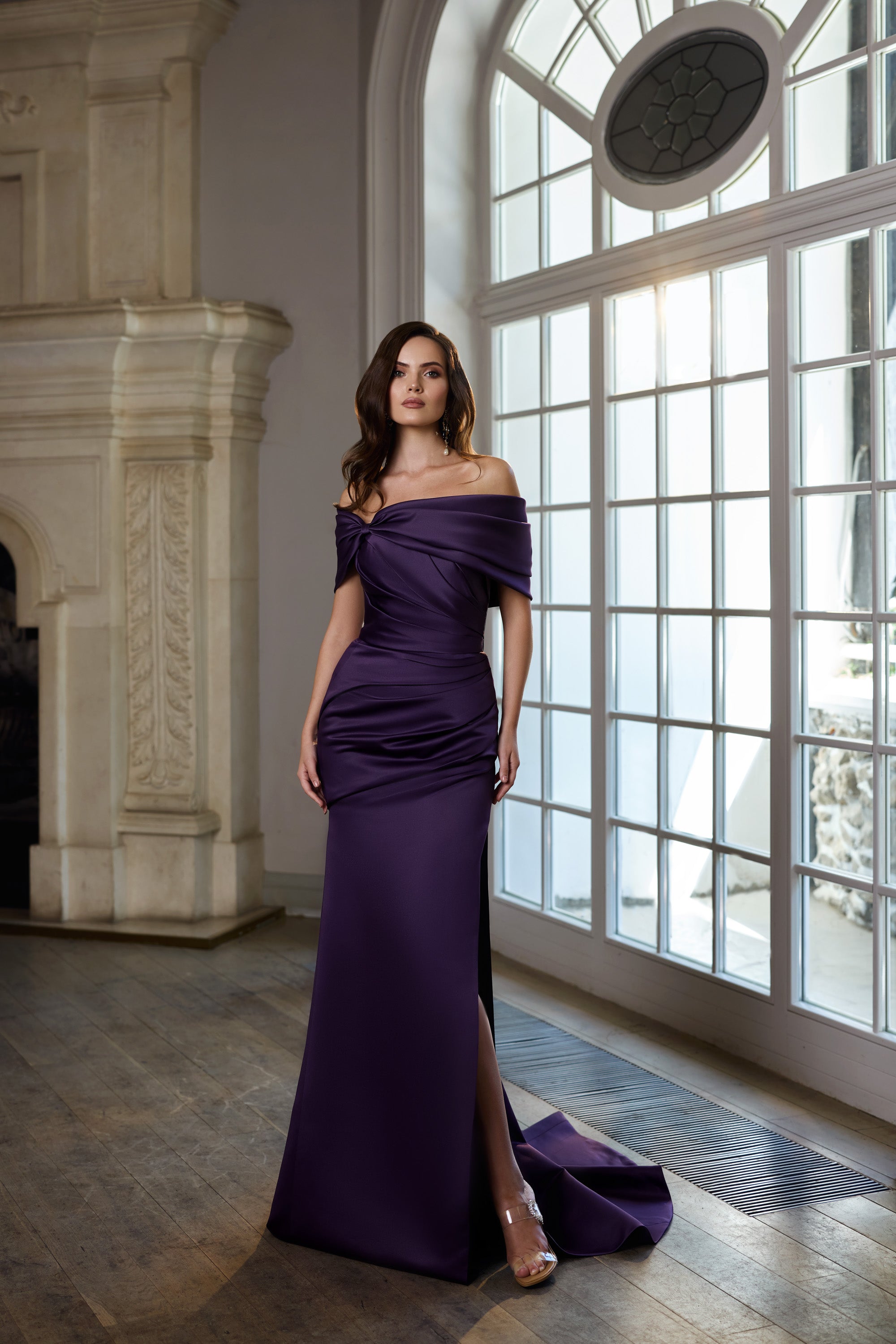 Deep purple evening dress with an off-the-shoulder neckline, ruched waist, thigh-high slit, and train