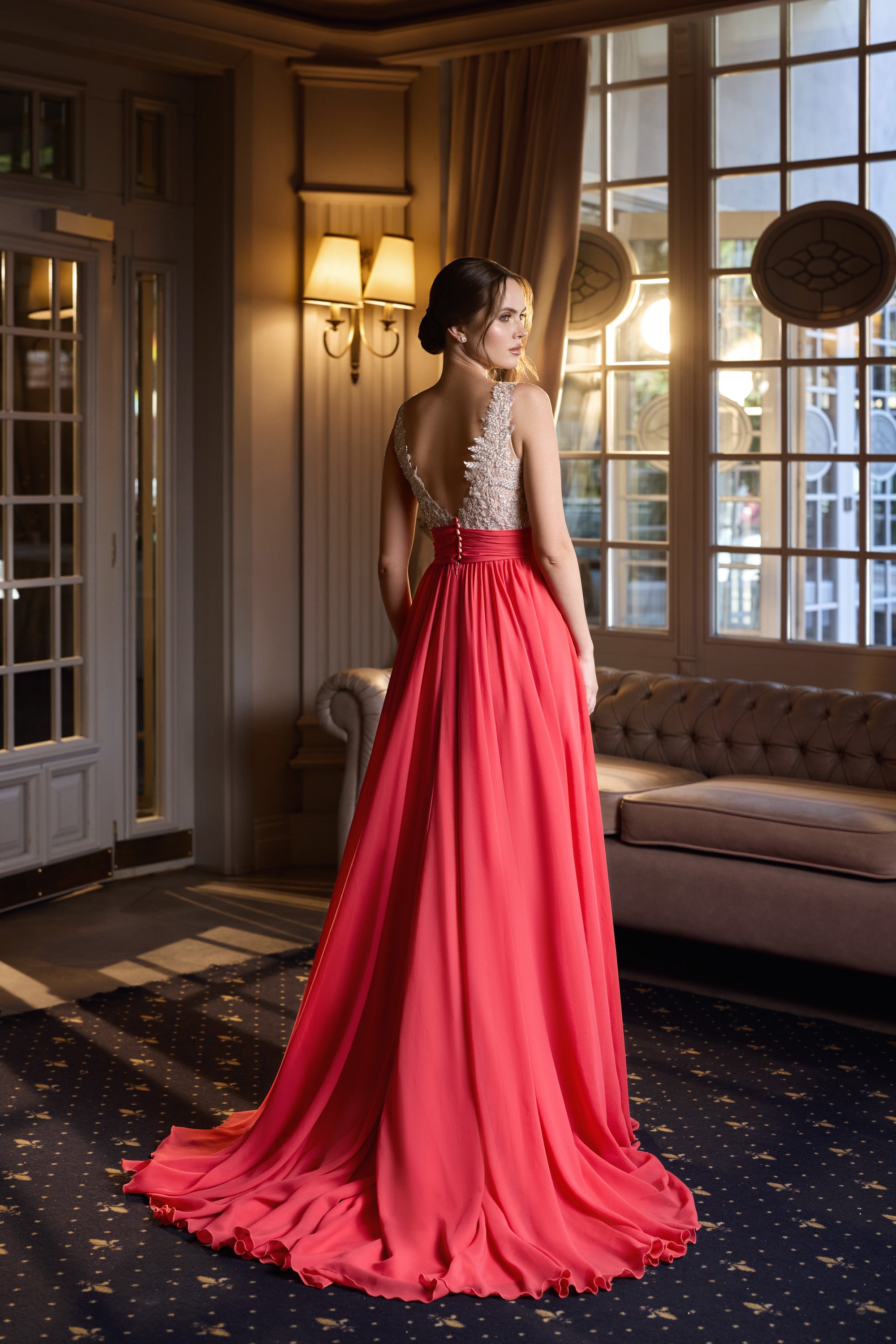 Red evening dress with a low open back, sparkling beaded bodice, flowing skirt, and a long pooled train