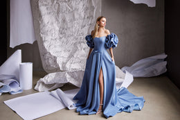 Blue satin evening dress with voluminous puff sleeves, an off-shoulder neckline, thigh-high slit, and train