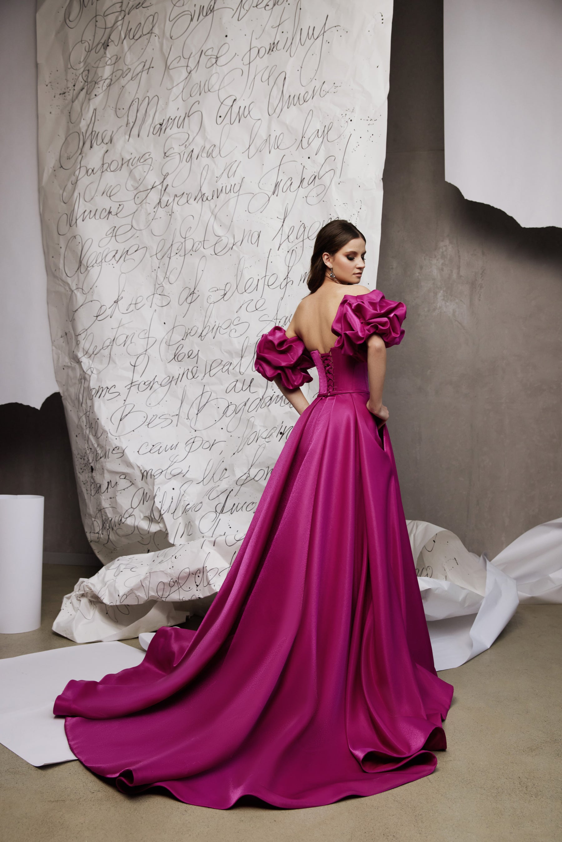 Magenta satin evening dress with dramatic puff sleeves, exposed upper back, and a sweeping floor-length train