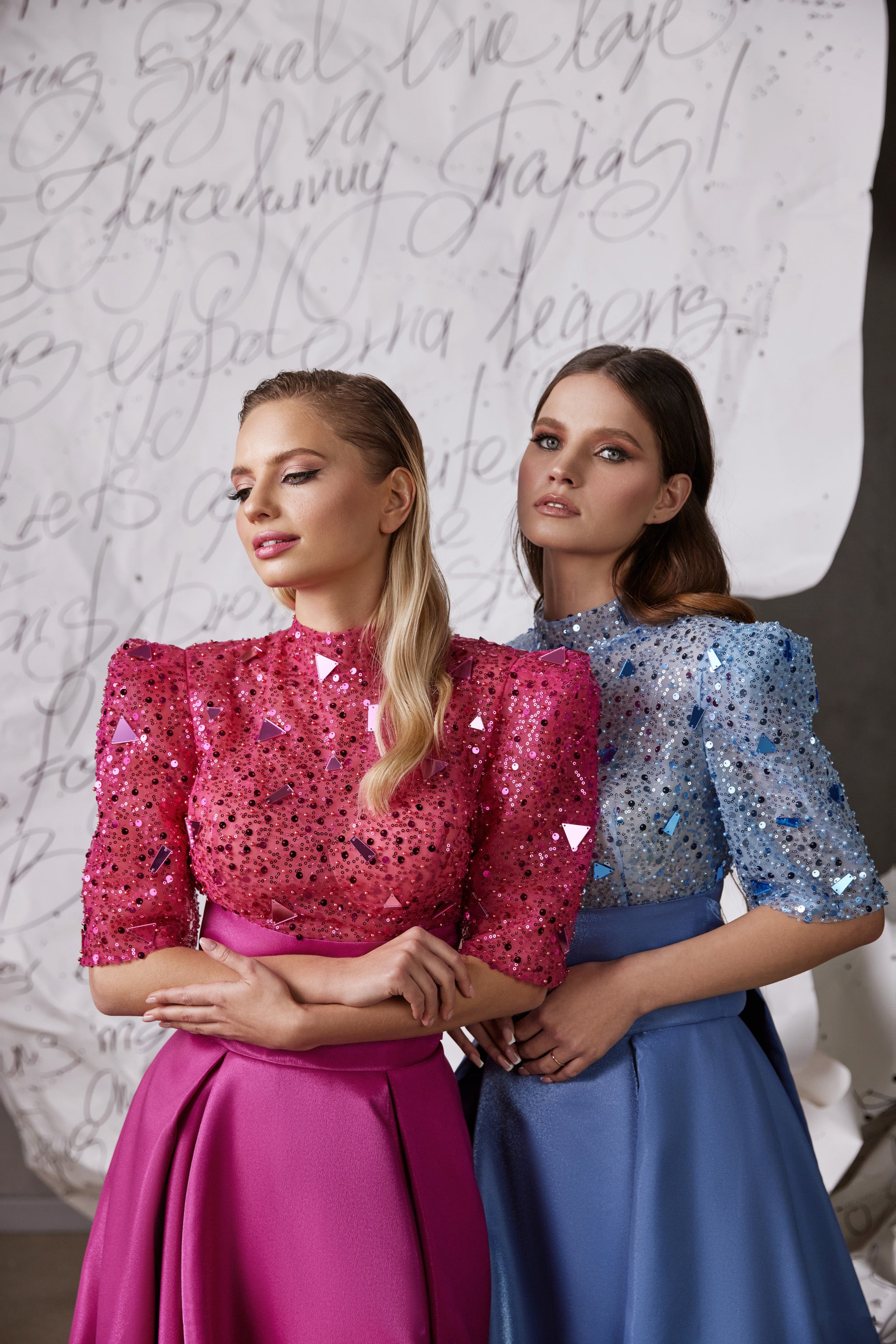 Close-up of pink and blue glitter evening dresses with high necklines, three-quarter sleeves, and jeweled bodices