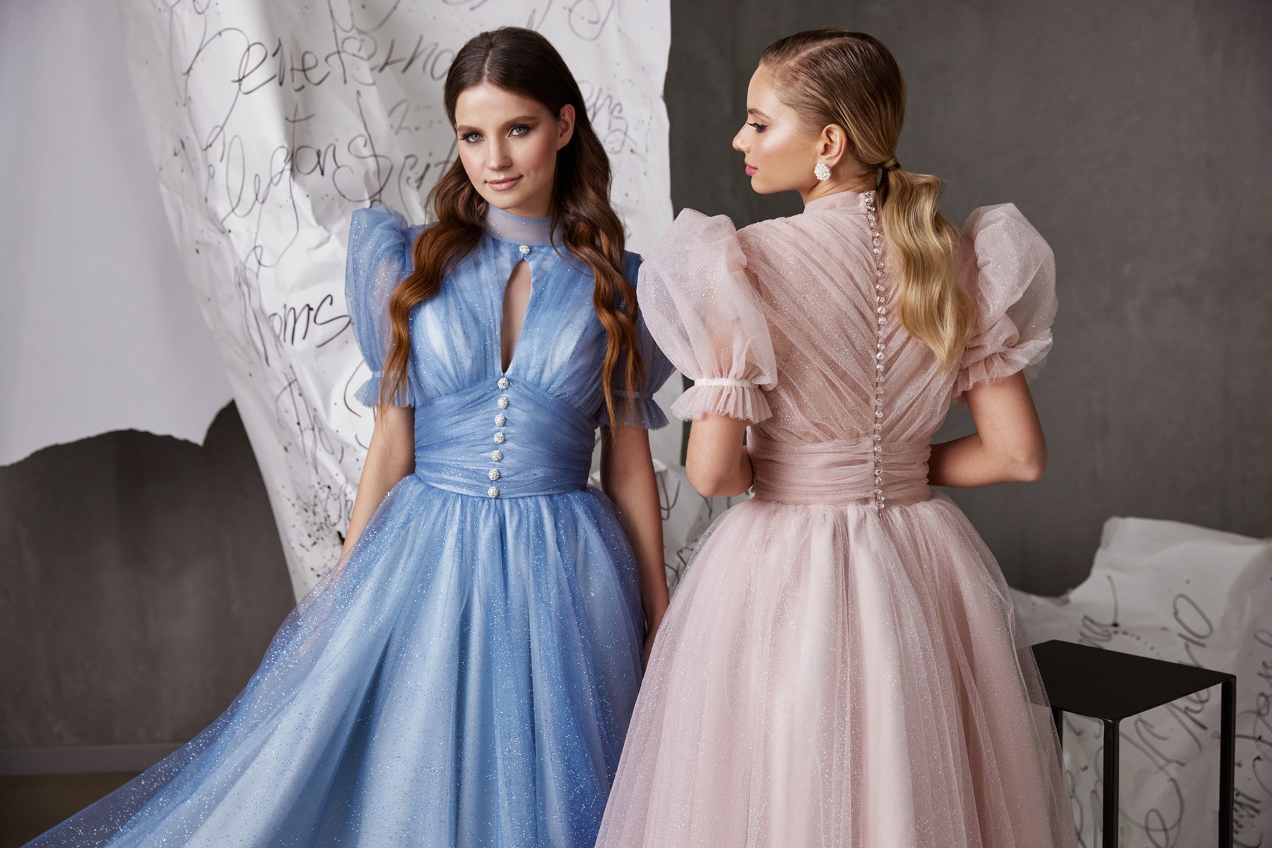 Blue and blush glitter tulle evening dresses with fitted waists, puff sleeves, and the blush dress's buttoned back