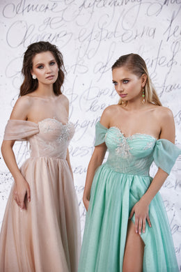 Close-up of blush and mint evening dresses with off-the-shoulder sleeves, sparkling bodices, and a visible slit