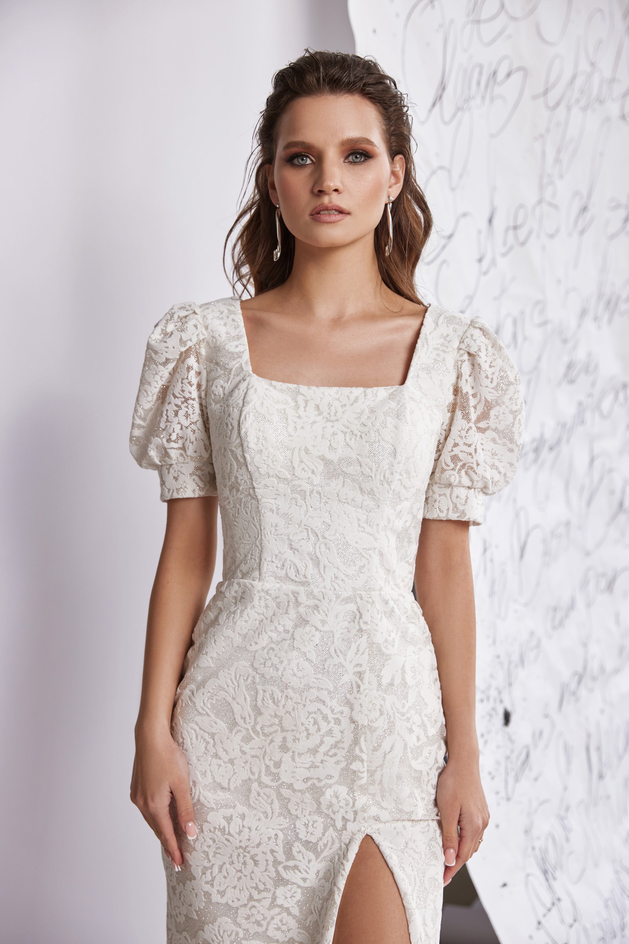 White lace evening dress with a square neckline, puff sleeves, fitted pencil silhouette, and front slit