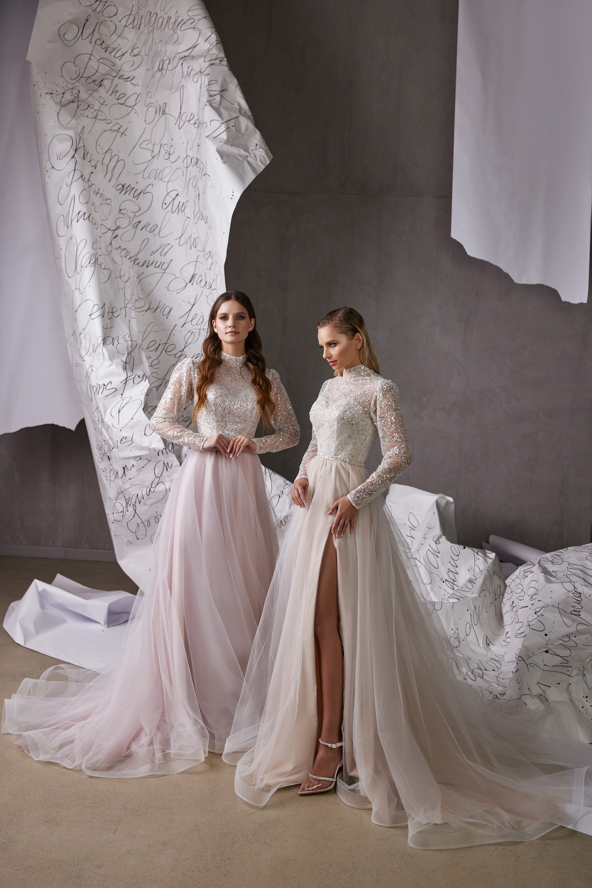 Pale pink and ivory evening dresses with high necklines, embellished long sleeves, flowing tulle skirts, and a front slit