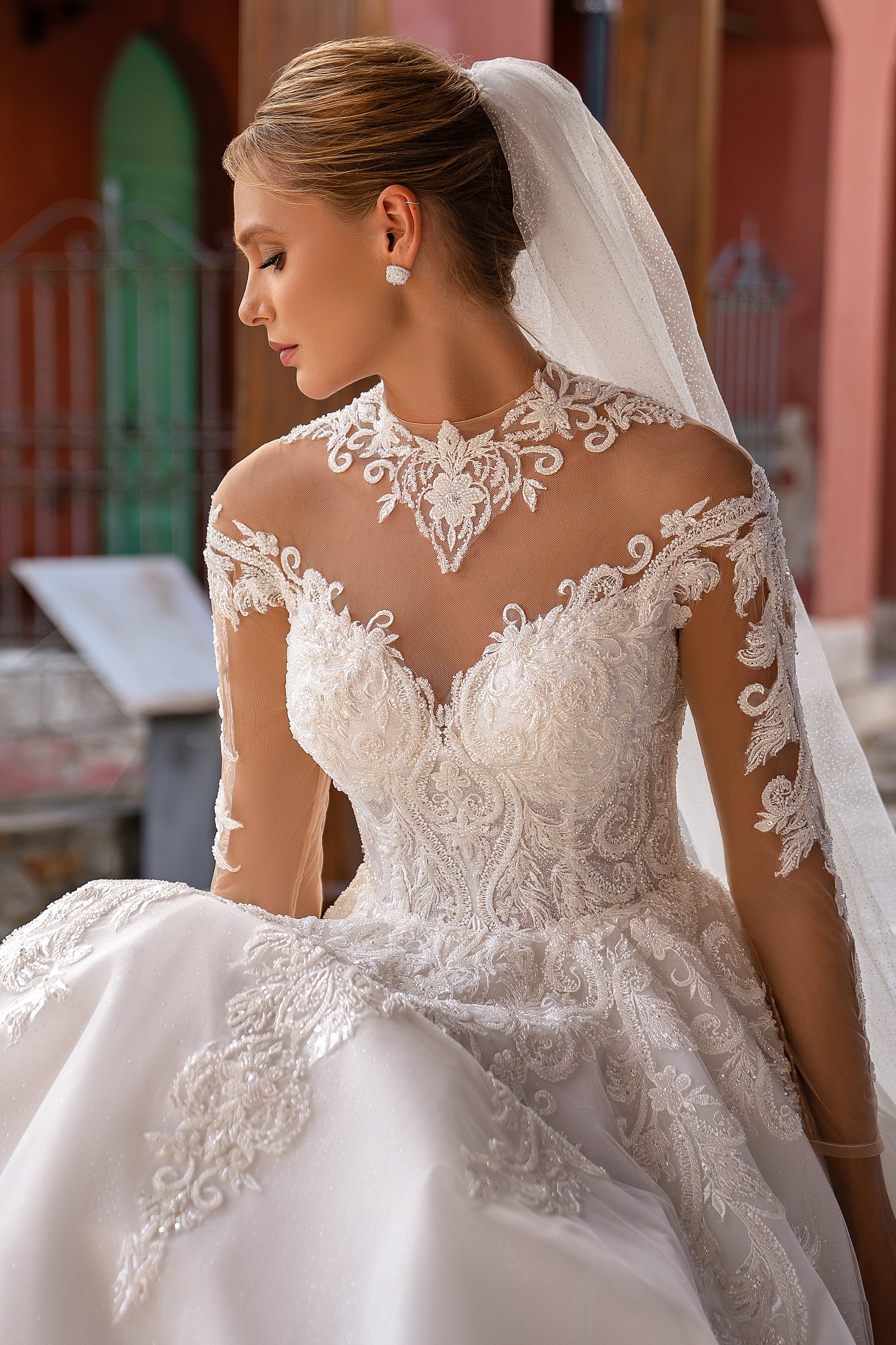 Sparkling wedding veil gathered at the hairstyle and draped behind a beaded lace bridal bodice