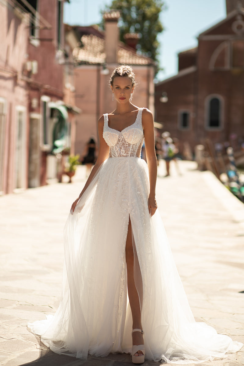Ivory A-line wedding dress with a beaded lace bodice, thin straps, front slit, and long train