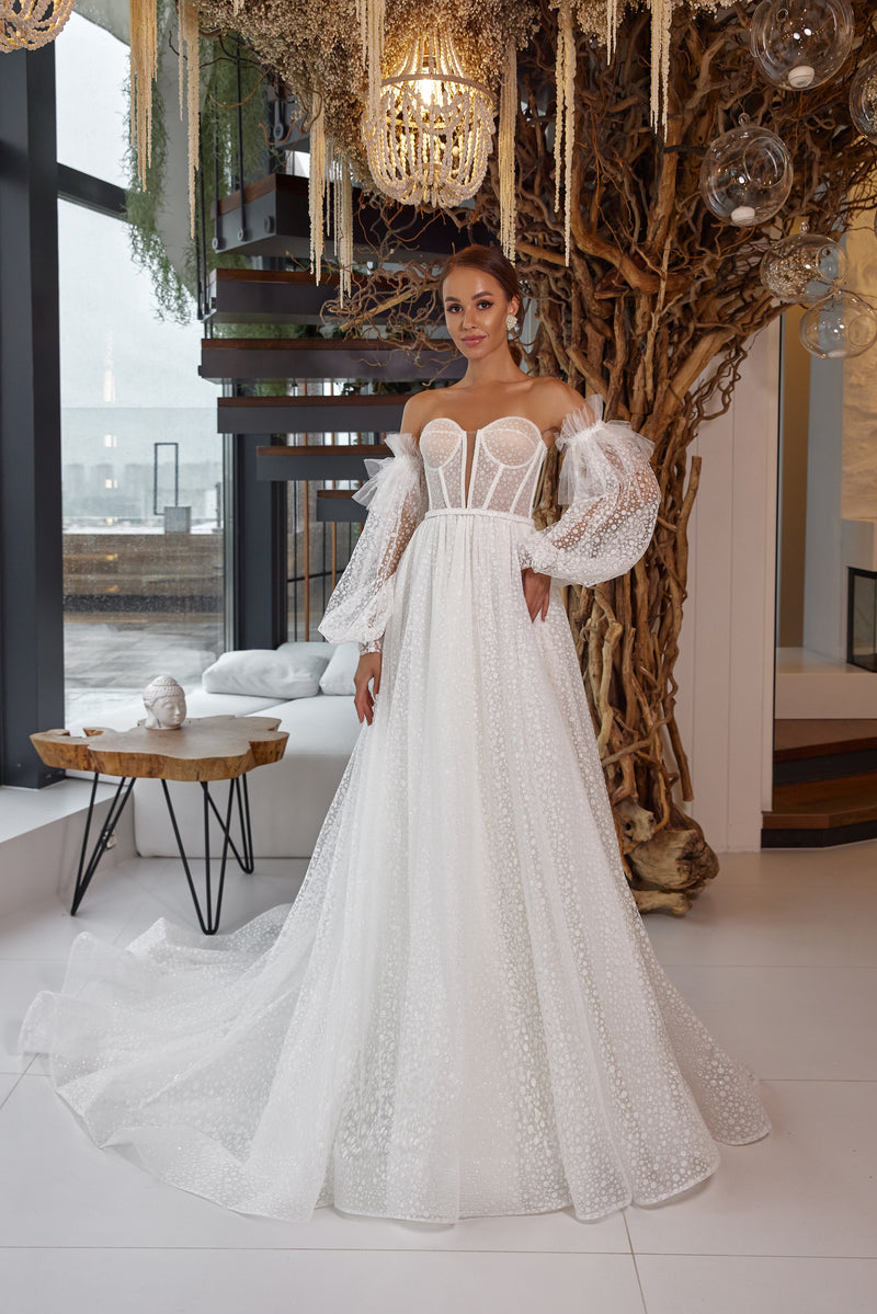 Ivory A-line wedding dress with a sparkling tulle skirt, sweetheart bodice, off-the-shoulder bishop sleeves, and train