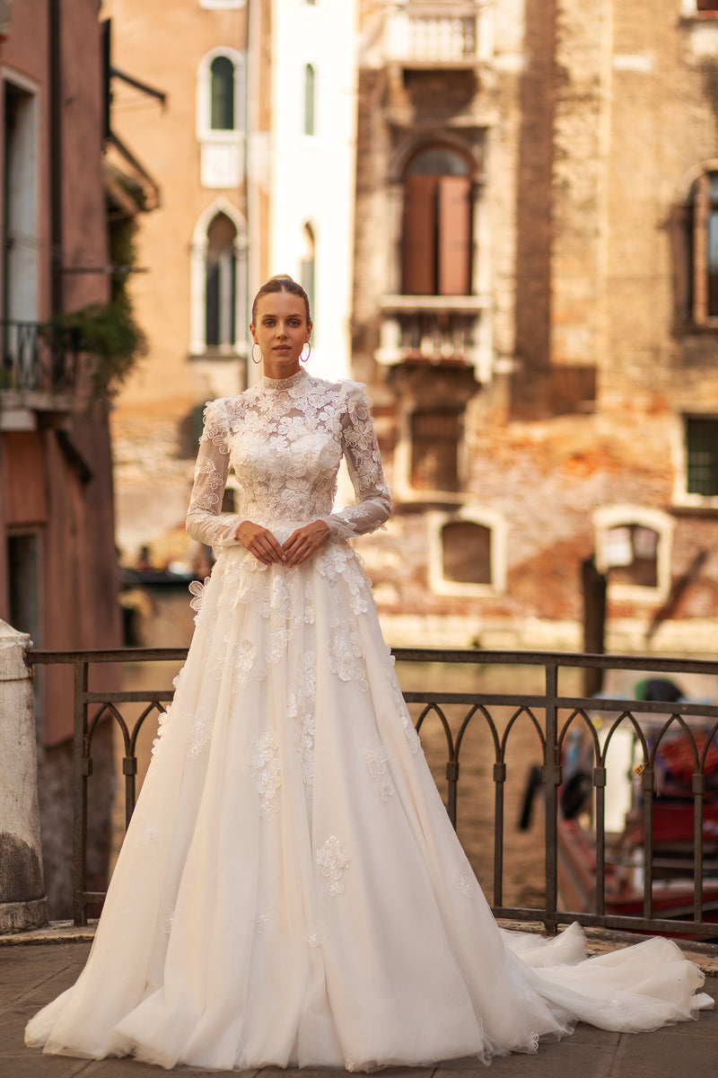 Ivory A-line wedding dress with a high neckline, long sleeves, floral lace bodice, and sweeping train