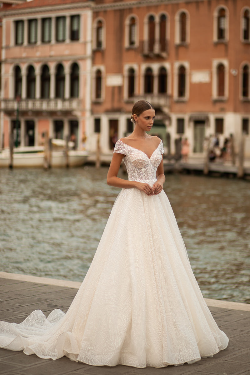 Ivory ball gown wedding dress with a V-neckline, short sleeves, beaded lace bodice, and long train