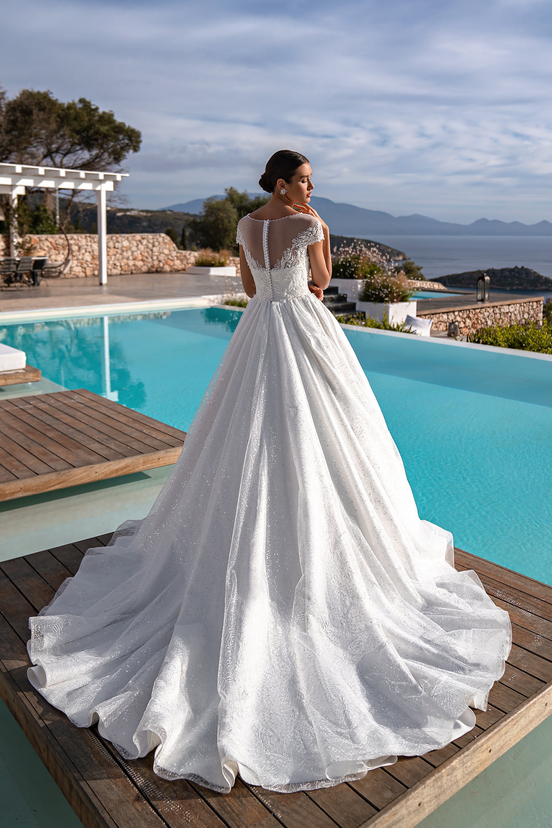 White wedding dress with an illusion lace back, short sleeves, full ball gown skirt, and sweeping train