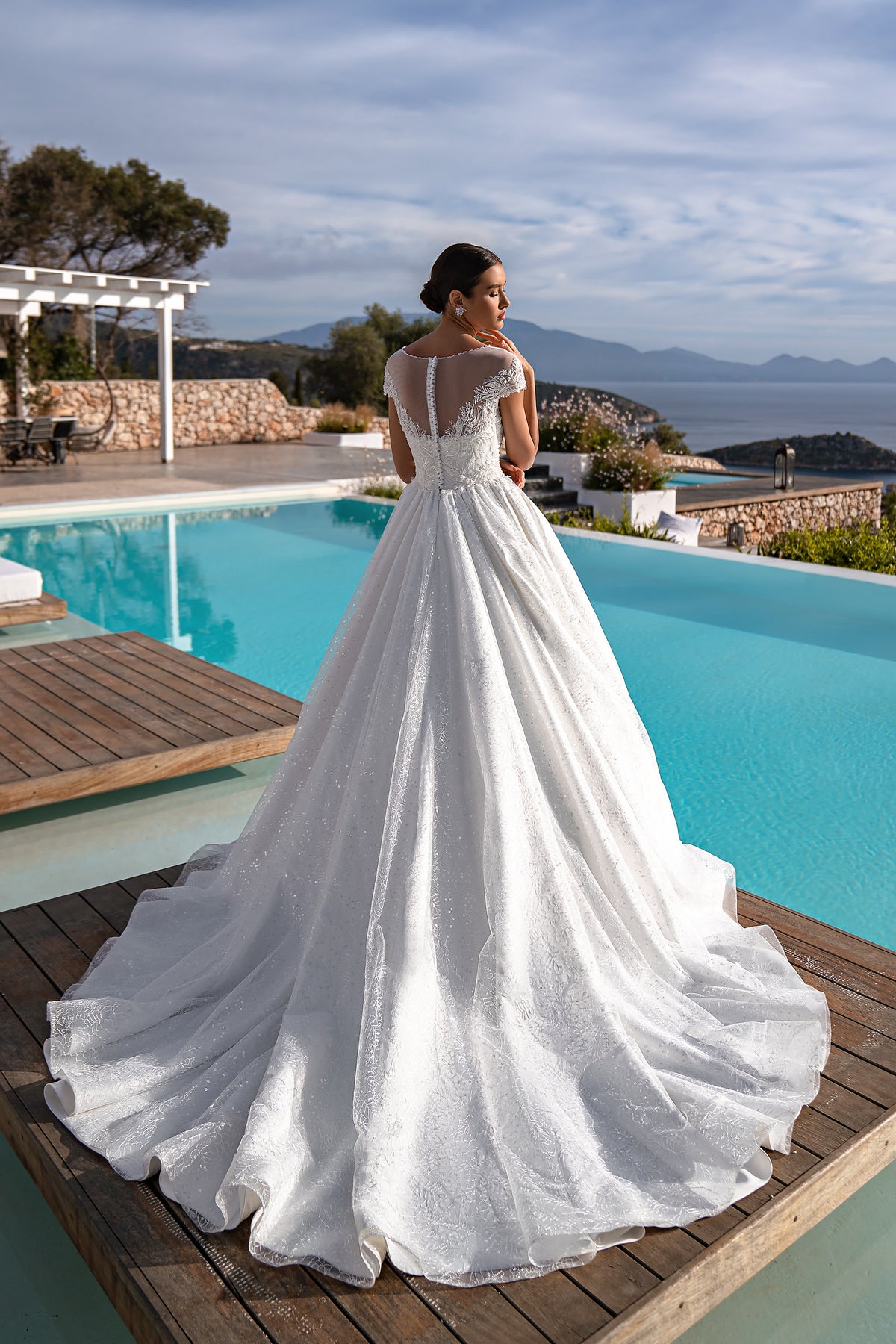 White wedding dress with an illusion lace back, short sleeves, full ball gown skirt, and sweeping train
