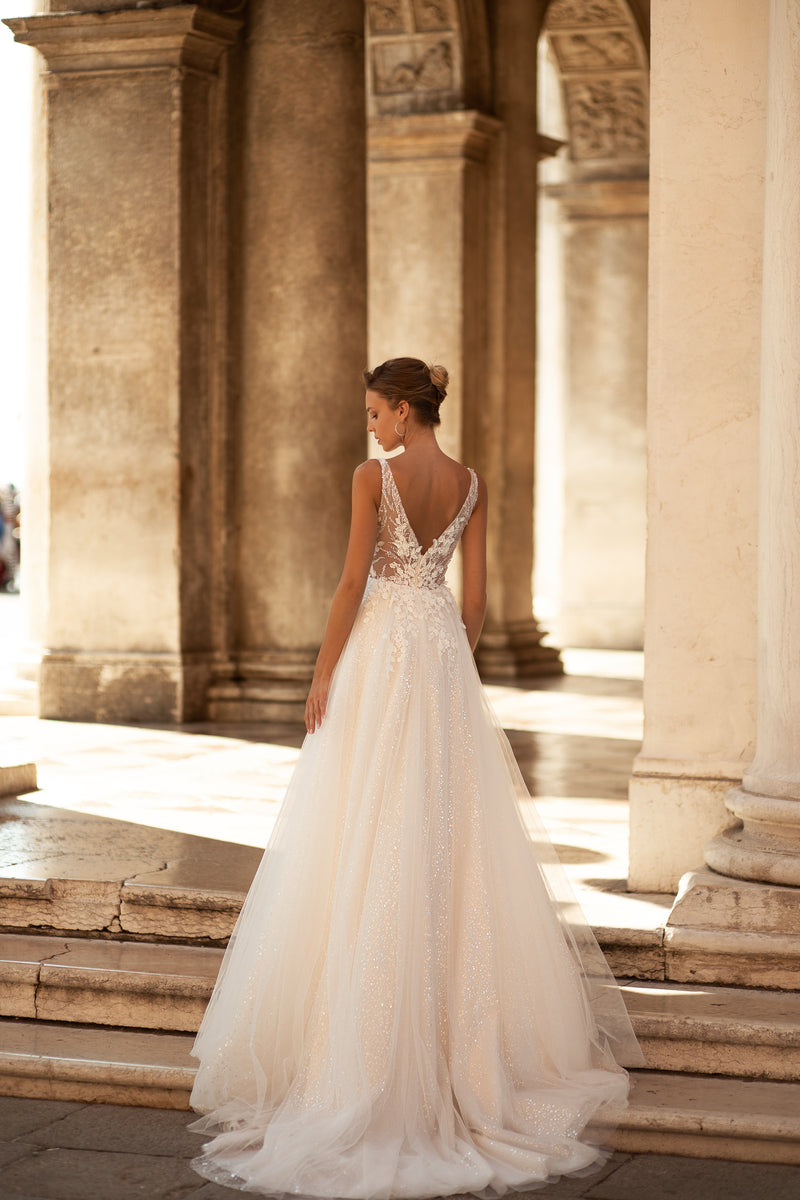 Ivory wedding dress with an open V-shaped lace back, narrow straps, and a flowing tulle train