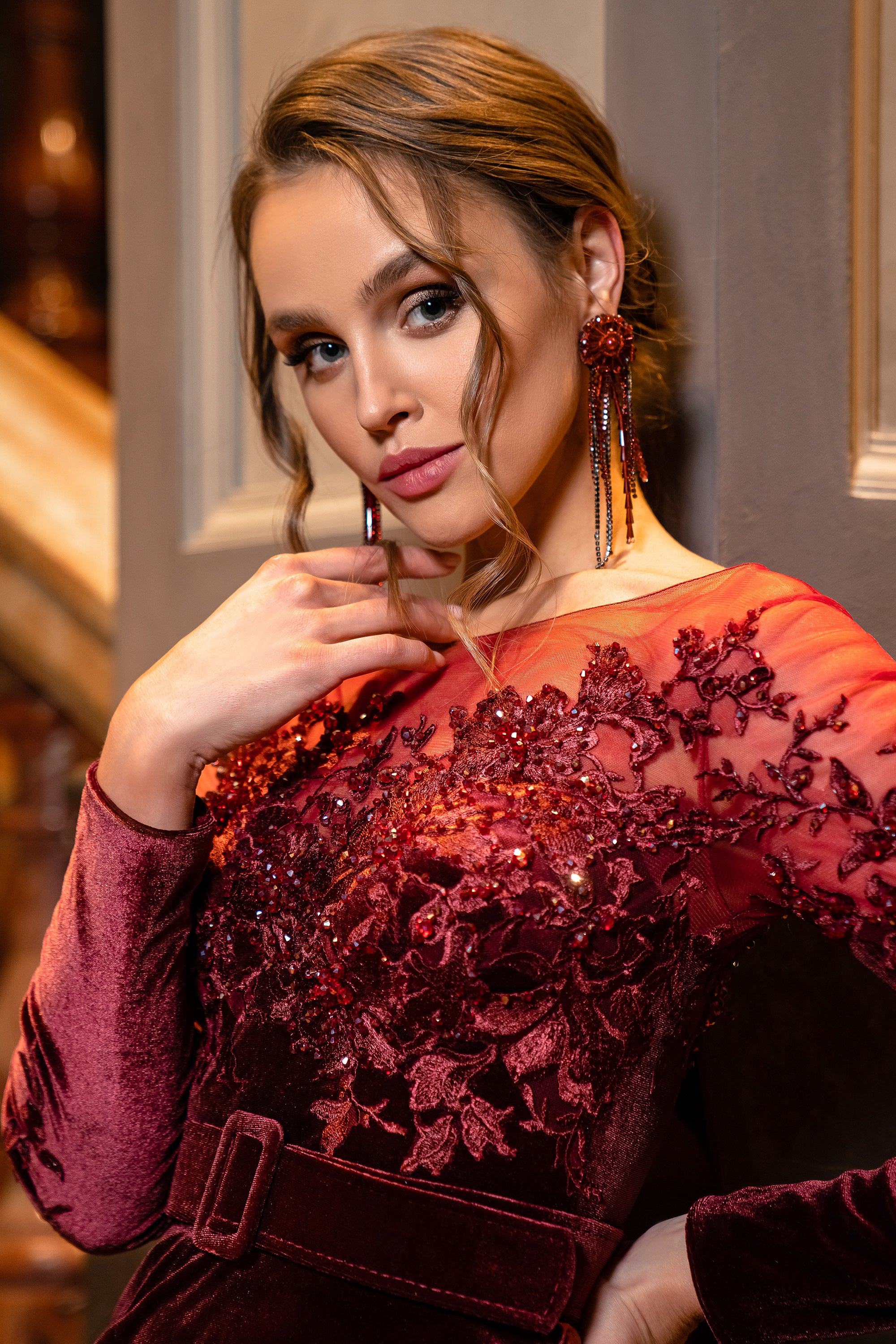 Close-up of a burgundy evening dress bodice with floral beadwork, long sleeves, and a velvet belt