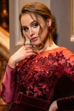 Close-up of a burgundy evening dress bodice with floral beadwork, long sleeves, and a velvet belt