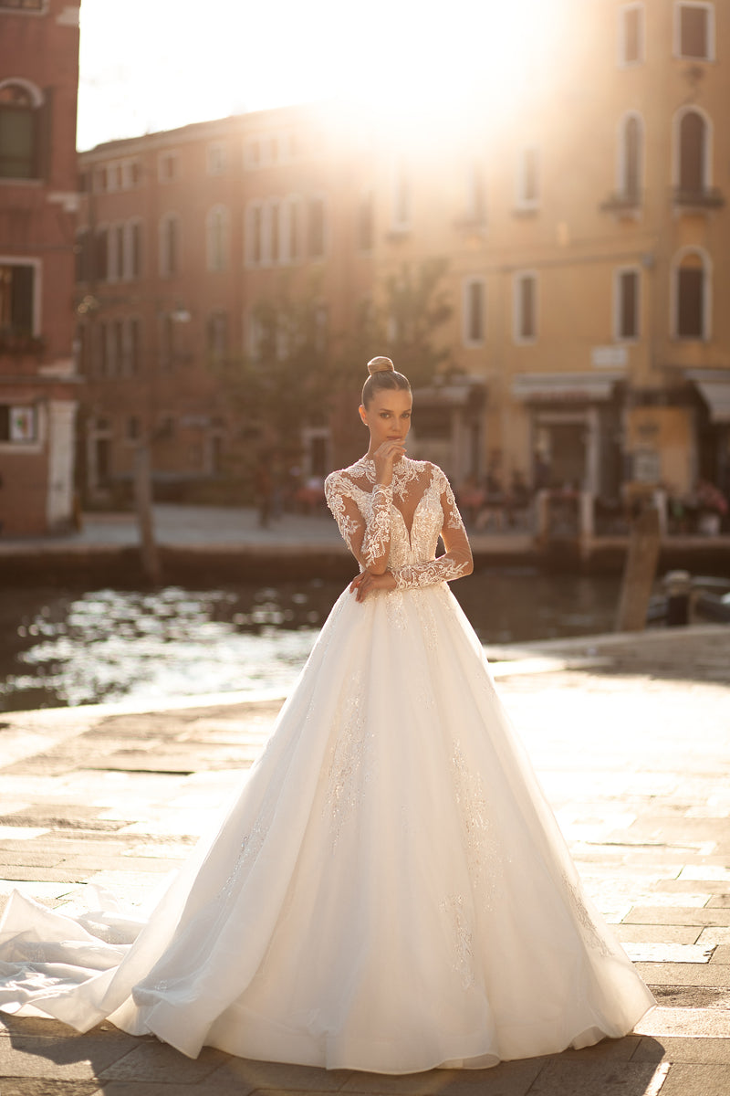 Ivory ball gown wedding dress with sheer lace long sleeves, a V-neck illusion bodice, and a full flowing skirt