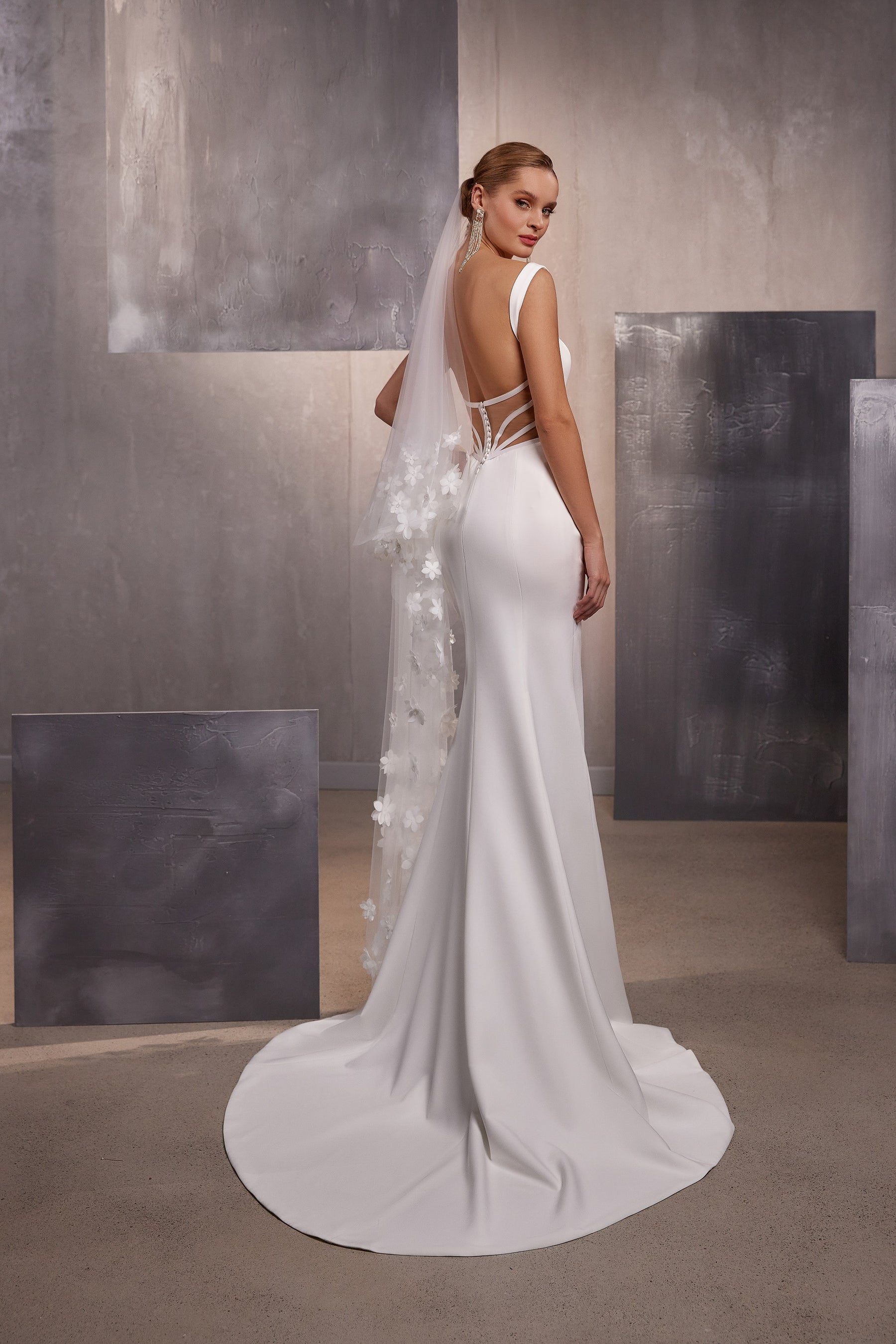 Long sheer wedding veil with scattered white floral appliqués draped over the back of a fitted gown