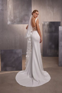 Long sheer wedding veil with scattered white floral appliqués draped over the back of a fitted gown