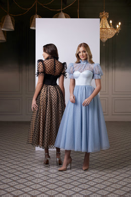 Black evening dress with sheer polka dot puff sleeves, a defined corset waist, and a tea-length full skirt