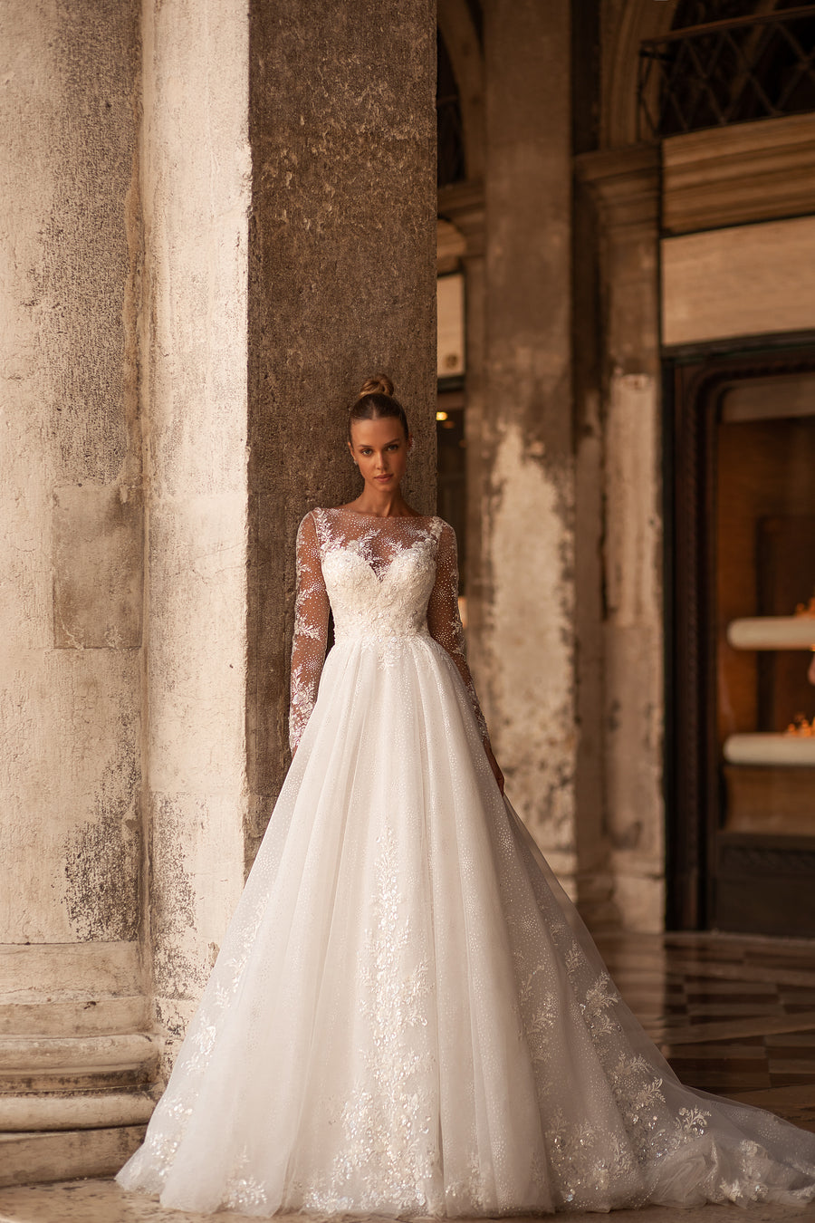 Ivory A-line wedding dress with sheer long sleeves, sparkling lace, and a sweeping train