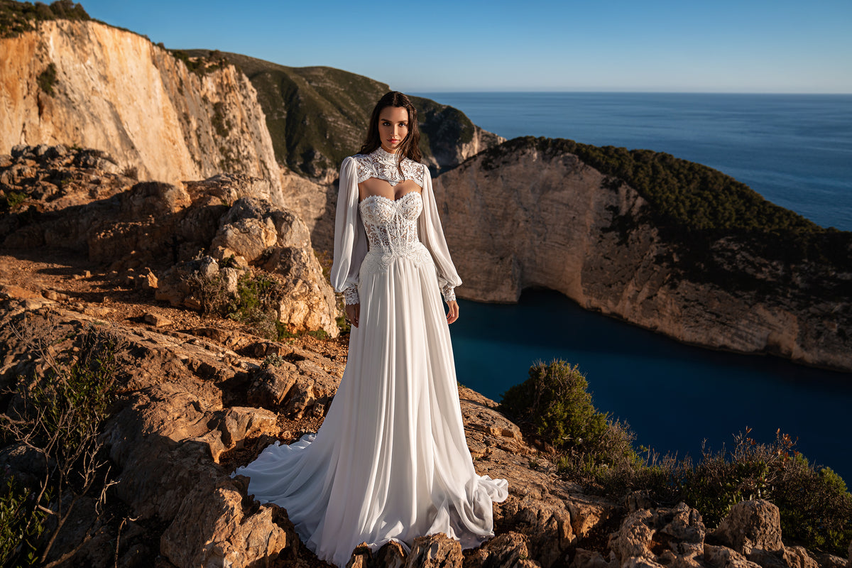 Full-length ivory wedding dress with a lace bodice, high neckline, sheer long sleeves, and extended train
