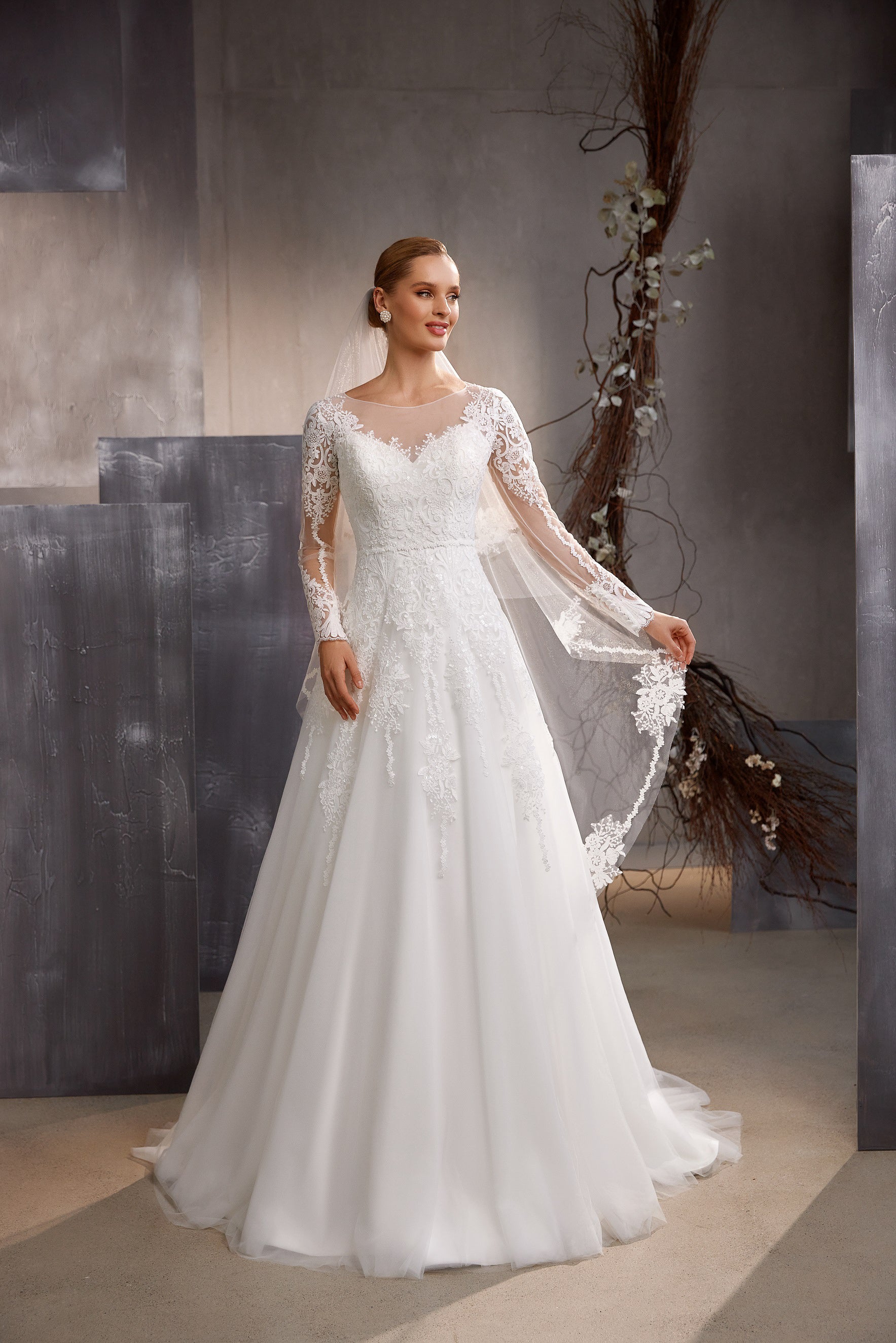 White wedding veil shown from the front, with sheer layers and ornate floral lace edging cascading beside the gown