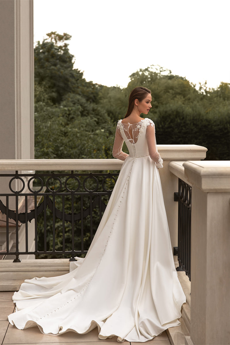 Sheer lace back with covered buttons on an ivory wedding dress with long sleeves and a flowing train
