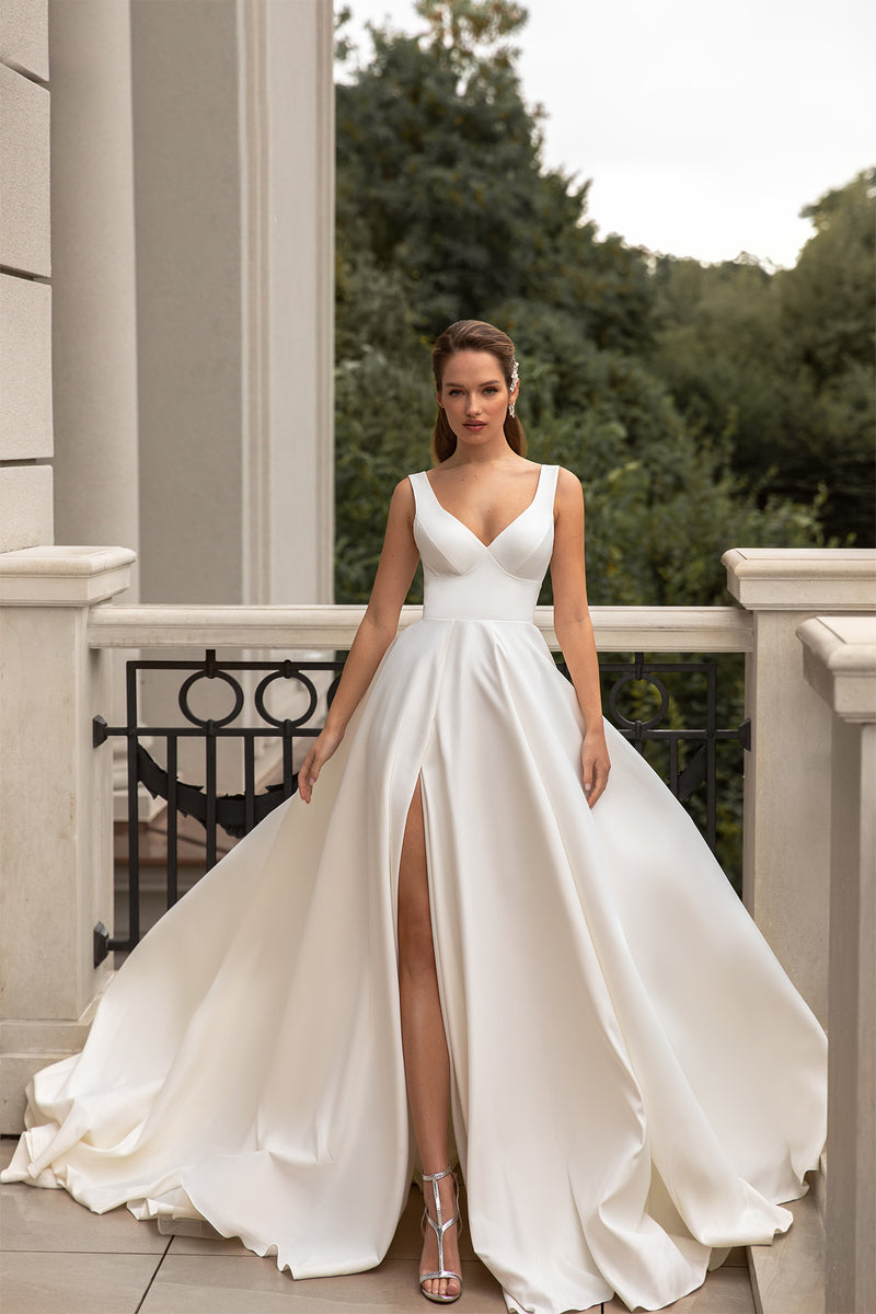 Ivory satin wedding dress with a deep V-neckline, sleeveless bodice, full skirt, thigh-high slit, and train
