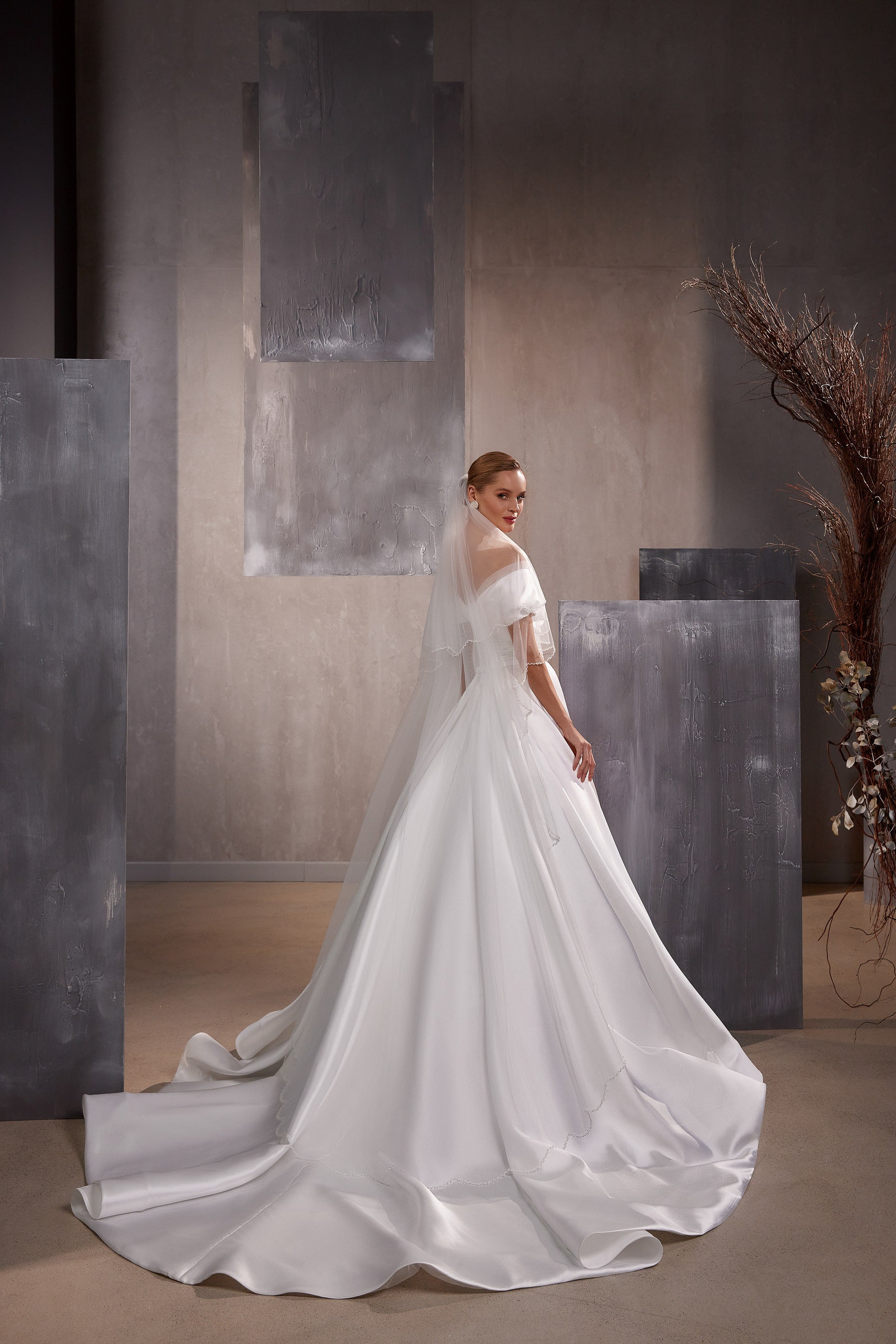 Long white wedding veil draped over the shoulders with layered fabric and a wide flowing edge