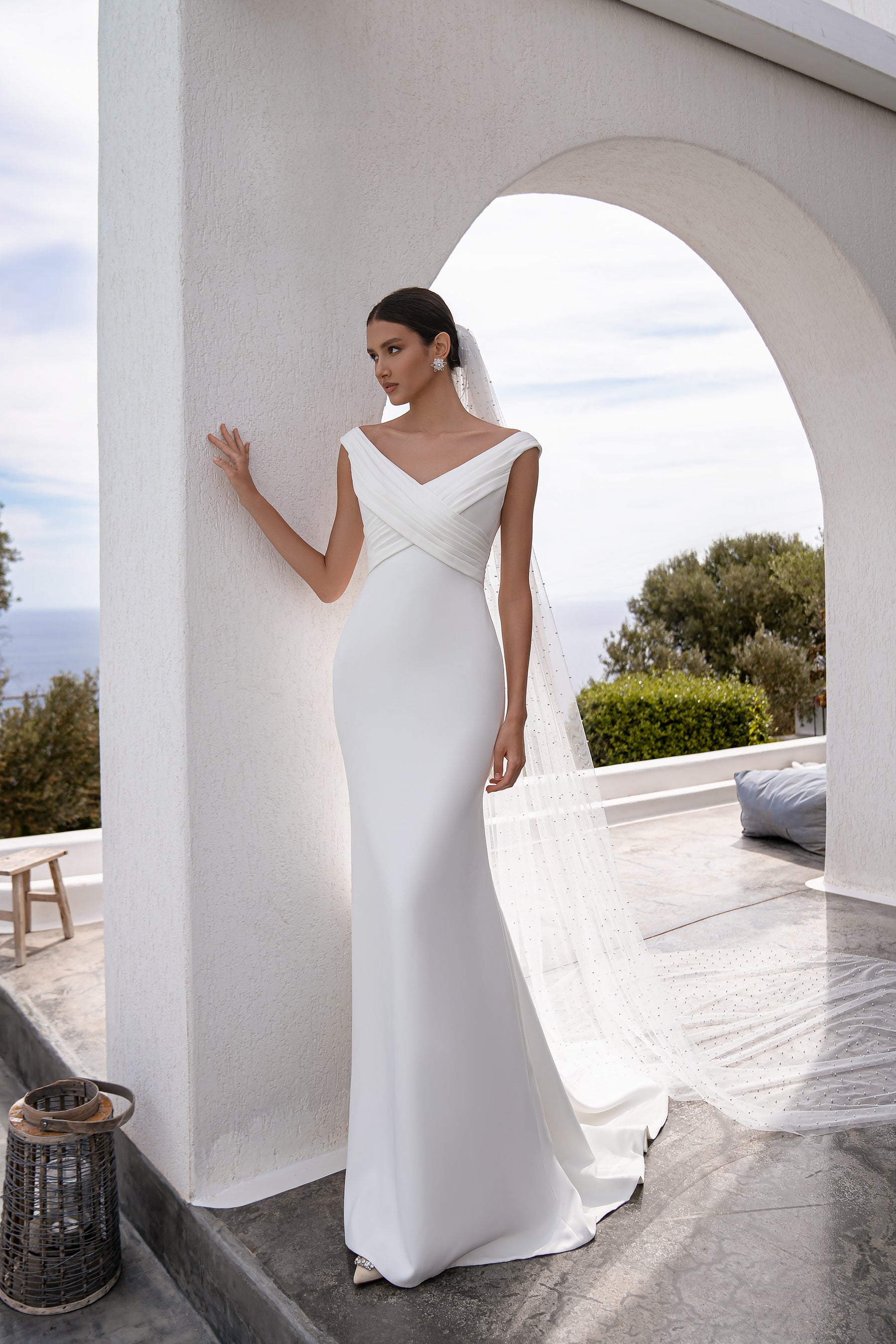 White pearl-dotted wedding veil cascading from the back with a translucent tulle drape