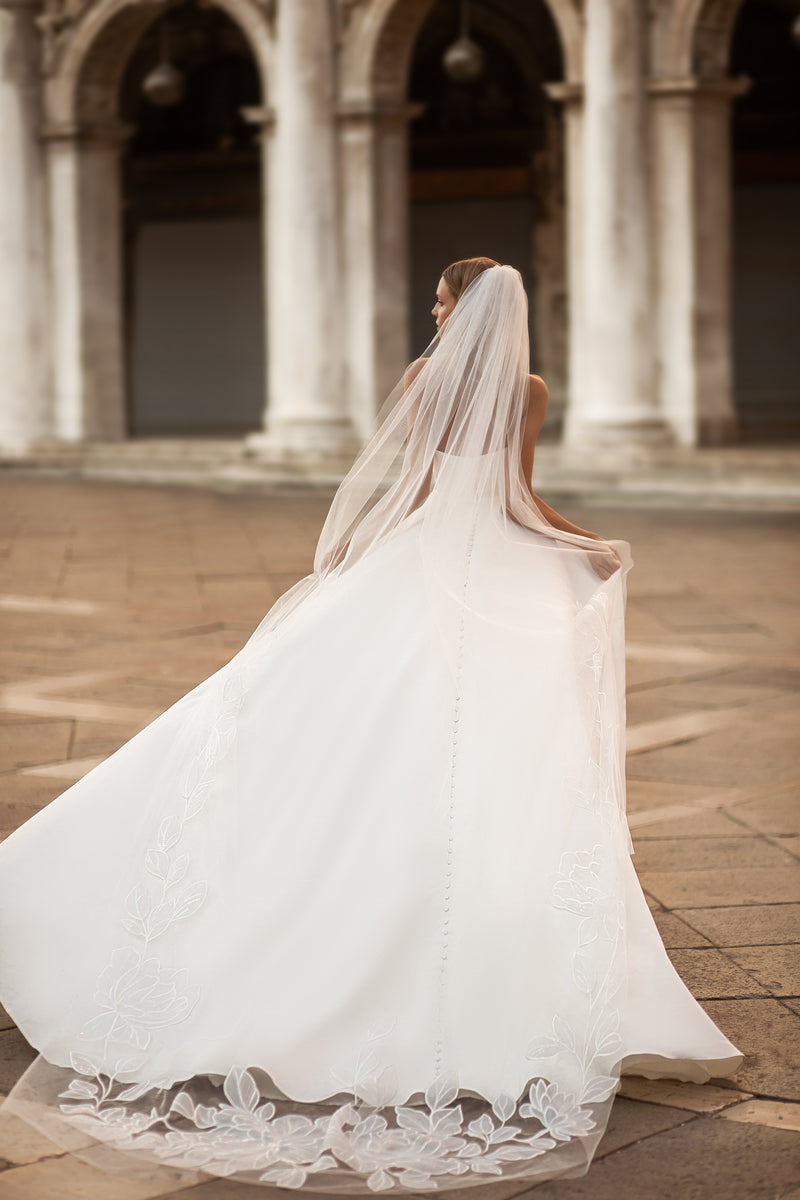 Buttoned back and sweeping train with floral lace edging on a white wedding dress